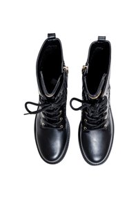 Une paire de bottines noires en cuir à lacets, avec oeillets dorés et fermetures éclair sur le côté, vues d'en haut sur un fond blanc.