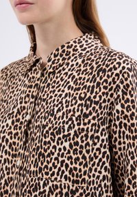 Leopardikuosisessä kauluspaita, jossa on rintatasku, valmistettu kevyestä kankaasta, jossa on sileä pinta ja maanläheinen värimaailma.