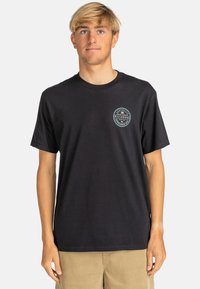Black cotton t-shirt with round neckline and short sleeves, featuring a circular logo on the left chest with white and blue accents.