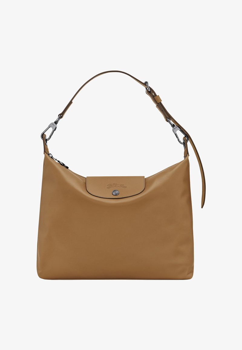 Tan synthetic shoulder bag with a rounded shape, a flap closure, embossed logo, and silver hardware accents. Adjustable strap included.