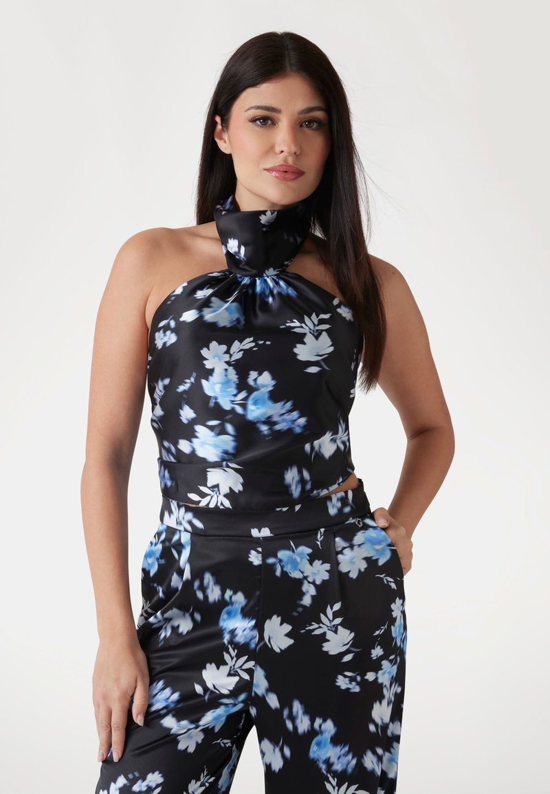 Crni halter top s plavim cvjetnim uzorkom, s detaljem čvora na vratu. Glatki satin materijal s uskim krojem.