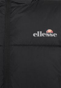 Svart puffjacka med kviltade sektioner, dragkedja fram och en vit logotyp "ellesse" på övre vänstra sidan.