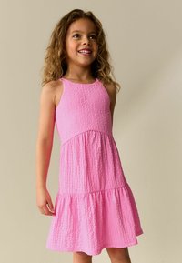 Roza obleka brez rokavov s teksturirano tkanino, oprijetim življenjem in razširjenim večslojnim spodnjim delom, z okroglim izrezom in tankimi naramnicami.