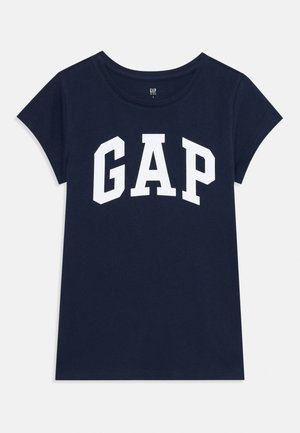 Tamnoplav majica od pamuka s kratkim rukavima, sa bijelim "GAP" logotipom na prednjoj strani u podebljanom, zakrivljenom fontu.
