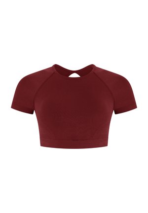 Top court rouge avec des manches raglan courtes, un col rond et une petite découpe dans le dos. Tissu légèrement texturé avec une coupe ajustée.