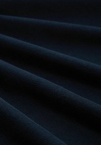 Marineblaue Stoff mit glatter Textur, der weiche, fallende Falten und ein einheitliches Muster aufweist. Licht reflektiert subtil auf seiner Oberfläche.