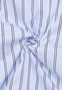 Tessuto di cotone con uno sfondo azzurro chiaro e strisce verticali blu scuro, caratterizzato da una trama testurizzata che aggiunge profondità.