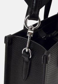 Borsa nera realizzata in materiale testurizzato con accentuazioni in hardware argentato, caratterizzata da un attacco ad anello e una tracolla in pelle nera elegante.