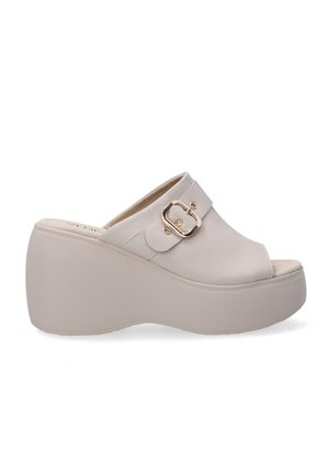 Beige platform mules made of smooth leather, featuring a wide strap with a gold-toned buckle, rounded open toe, and textured sole.