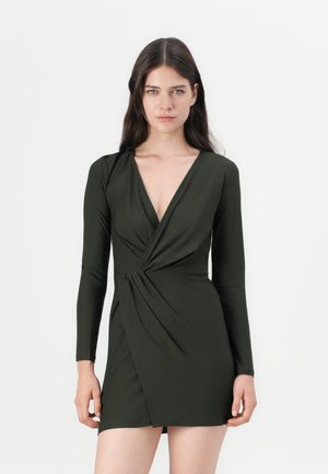 Dunkelgrünes Minikleid mit langen Ärmeln, V-Ausschnitt und verdrehtem Vorderteil. Hergestellt aus glattem, dehnbarem Material.