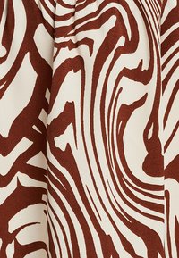 Tissu en coton avec un motif abstrait ondulé marron et crème, présentant une texture lisse et un design fluide, idéal pour diverses applications textiles.