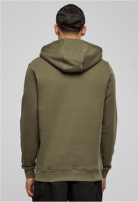 Felpa verde oliva con cappuccio regolabile, polsini e orlo a costine, realizzata in un tessuto morbido. Il retro presenta una finitura liscia e priva di decorazioni.