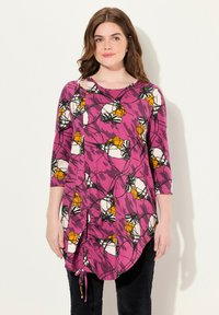 Túnica de manga larga en color rosa con estampado floral en blanco y naranja. Cuello redondo, detalle fruncido en los laterales y dobladillo curvado. Confeccionada en tela ligera.