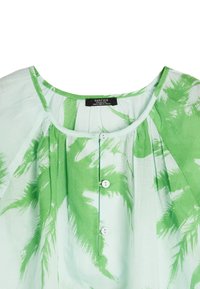 Zielona i biała lniana bluzka z okrągłym dekoltem, zapięciem na guziki oraz abstrakcyjnymi wzorami liści. Miękka tekstura z marszczonymi detalami.
