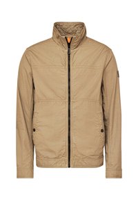 Beige zip-up jacket with a stand collar, textured fabric, two side pockets, and contrasting black zipper. Features stitched seams and logo detail.