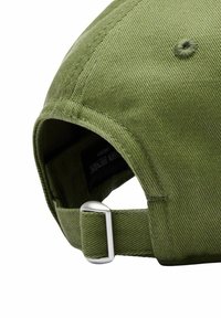 Vihreä puuvillainen baseball-lippu, jossa on kaareva lippapää, säädettävä metallihaka takana ja teksturoitu kangas. Sisäpuolen etiketti näkyvissä.