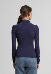 Marineblaue Langarmoberteil mit Stehkragen, tailliertem Design und leichtem Stoff. Verfügt über eine glatte Textur und minimalistischen Stil.