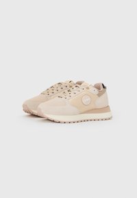 Lichtbeige sneakers met een bovenwerk van suède en synthetisch materiaal, een rond logo aan de zijkant en een gevoerde kraag. Rubberen zool met een gestructureerd profiel.