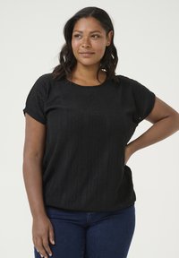 Zwarte top met korte mouwen, voorzien van een textuurpatroon, ronde halslijn en een relaxte pasvorm, gecombineerd met blauwe denim jeans.