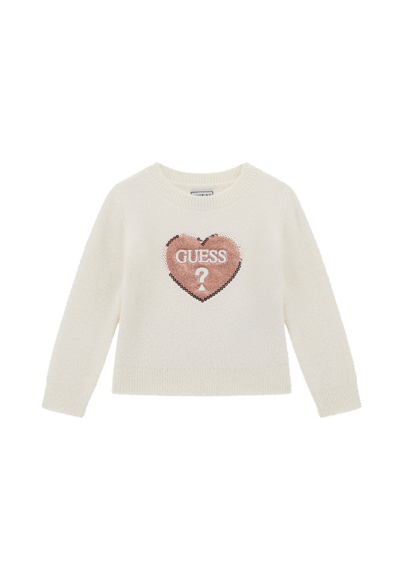 Maglione color crema con una texture morbida, caratterizzato da una patch a forma di cuore con paillettes di un rosa chiaro, sopra la quale è scritto "GUESS" e un punto interrogativo.