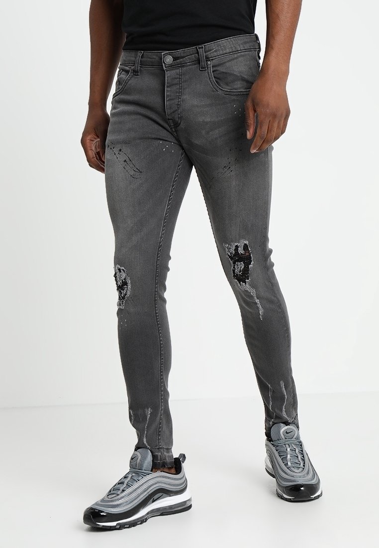 Jeans ajustados grises con detalles desgastados, incluyendo desgarros en las rodillas. Hechos de denim con un ligero estiramiento para mayor comodidad.