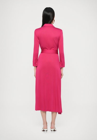 Φούξια φόρεμα με μακριά μανίκια, γιακά, ζώνη στη μέση και λεία υφή, φτάνει μέχρι τη μέση της γάμπας. Η πίσω όψη δείχνει μια αέρινη σιλουέτα.
