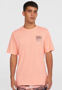 Lyserød kortærmet t-shirt lavet af bomuld, med et lille brystmotiv med tekst og soldesign i mørk lilla. Klassisk pasform.