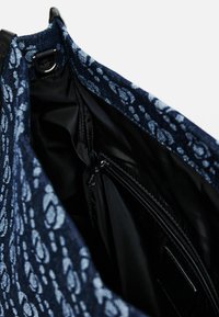 Borsa in tessuto blu navy con un motivo floreale testurizzato, dotata di una tasca interna con zip e un interno nero liscio.