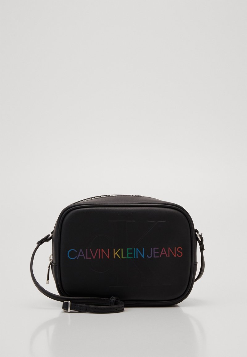 Borsa rettangolare nera con una texture liscia, con il testo in gradiente arcobaleno "CALVIN KLEIN JEANS" sul davanti e una tracolla regolabile.