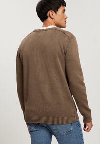 Brązowy sweter dzianinowy z prążkowanym dołem i mankietami. Posiada okrągły dekolt i teksturowany materiał, pokazany z tyłu w luźnym kroju.