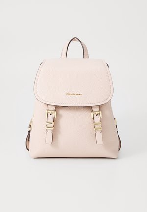 Petit sac à dos en cuir rose pâle avec rabat, sangles à boucle dorée et logo Michael Kors au centre sur le devant.