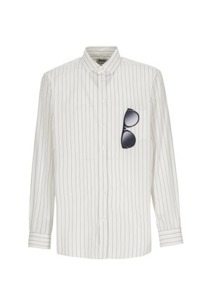 Camicia bianca a maniche lunghe con sottili righe nere verticali e occhiali da sole neri appesi nella tasca sinistra sul petto.