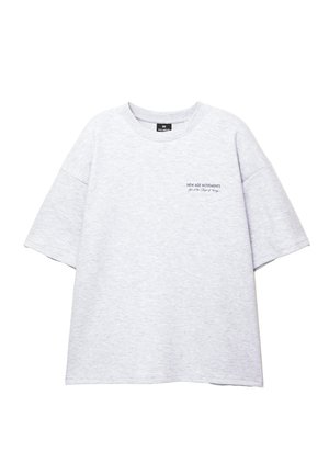 Graues, übergroßes T-Shirt aus Baumwolle mit Rundhalsausschnitt und kurzen Ärmeln. Auf der Brust in dunkler Schrift "NEW AGE MOVEMENTS" gedruckt.