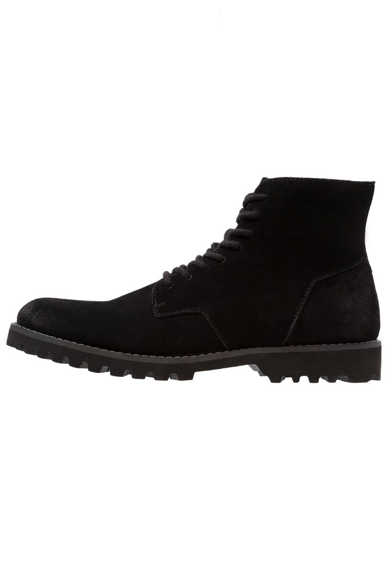 Botas de tobillo de ante negro con un acabado texturizado, punta redondeada y suela de goma con tacos. Presentan un cordón en la parte delantera y un eje de altura media.