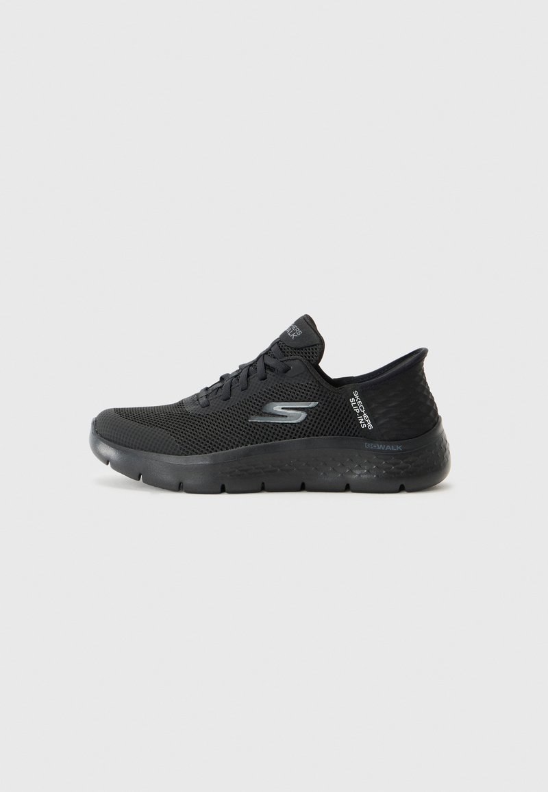 Chaussure de sport noire avec tige en mesh, semelle couverte et design flexible. Présente un logo et des accents texturés sur le talon.