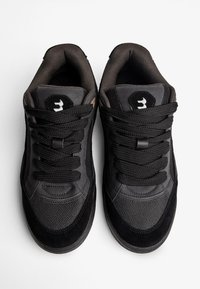 Adidași negri cu un amestec de plasă texturată și piele netedă. Vârf rotunjit, guler căptușit și șireturi tonale cu o etichetă logo pe limba pantofului.