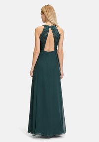 Langes türkisfarbenes Kleid mit einer Spitzenrückenverzierung und einem tiefen V-Ausschnitt. Verfügt über einen fließenden Rock und einen verdeckten Reißverschluss hinten.