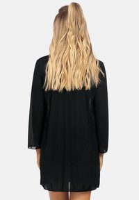 Czarny, lekki, sięgający kolan płaszcz z trzema ćwierć rękawami. Posiada gładką teksturę i luźny krój, bez widocznych akcentów.