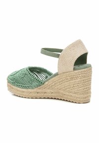 Sandalia cuña verde con bordado texturizado intrincado, diseño de punta abierta y un acento de tela a cuadros beige en el talón.