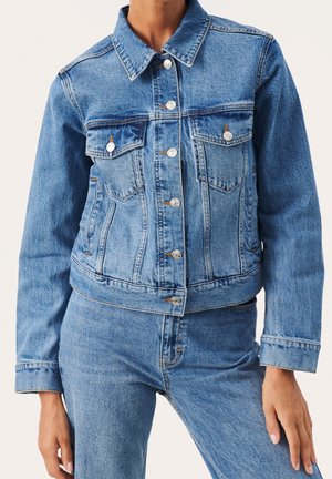 Jeansjacka i ljusblått med silverknappar, två bröstfickor och en kort design med slitna detaljer på tyget.