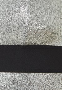 Gros plan d'un tissu métallique argenté avec une bande noire horizontale au milieu et une surface texturée et brillante.