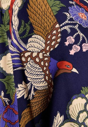 Tela con un patrón vibrante, que presenta un diseño de ave prominente en marrón, azul y rojo, sobre un fondo azul oscuro.