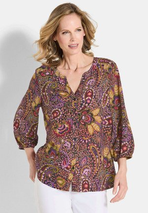 Bunt gemusterte Bluse mit einem Paisleymuster in lila, orange und olivgrün, einem V-Ausschnitt und dreiviertellangen Puffärmeln.