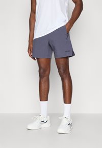 Hallituspruunid lühikesed püksid tekstuuriga materjalist, küljetaskud ja reguleeritav elastne vöökoht. Vasakule jalale on trükitud must "BORG" logo. Valged sportsockid ja tossud.