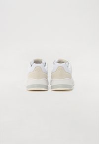 Fehér és bézs sneaker, hálós felső résszel, velúr részletekkel, párnázott nyakkal és átlátszó gumitalppal. Minimalista dizájn, lekerekített forma.