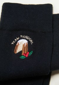 Calzini neri con una texture a coste, caratterizzati da un design ricamato di una torta guarnita con crema e due bacche rosse, etichettata "TEAM PANDORA."