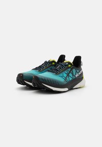 Scarpe da trail running con tomaia turchese e nera, dettagli gialli, design testurizzato e suola nera robusta per la trazione.