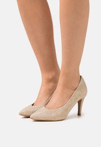 Beige lodičky s špičatou špičkou, texturovanou látkou a štíhlým, elegantním podpatkem. Hladký povrch s jemným leskem.