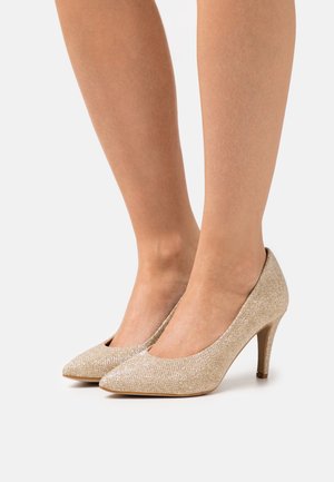 Beige högklackade skor med spetsig tå, textilmaterial och en smal, elegant klack. Slät yta med subtil lyster.