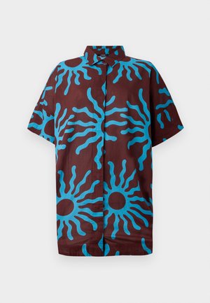 Valkoinen lyhythihainen paita ruskeasta kankaasta, jossa on suuria sinisiä auringonkuvioita, kaulus ja rento istuvuus.